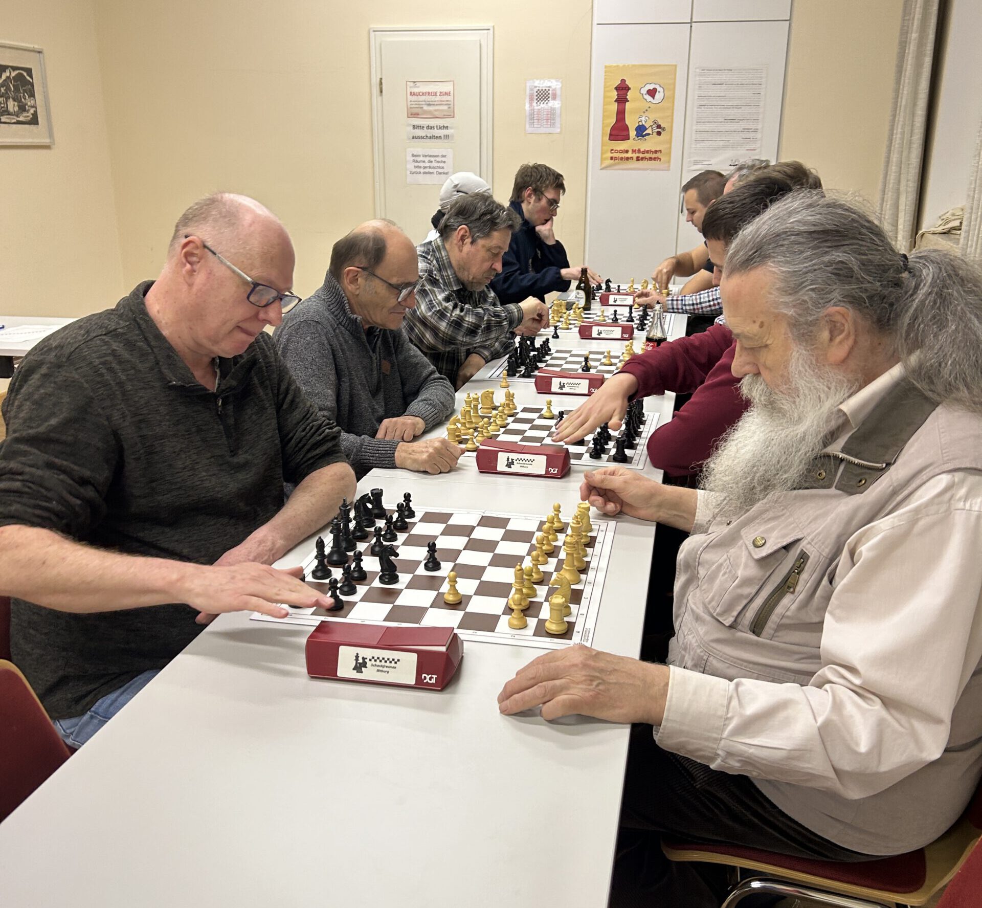 Mehrere Vereinsmitglieder konzentriert an den Schachbrettern.
